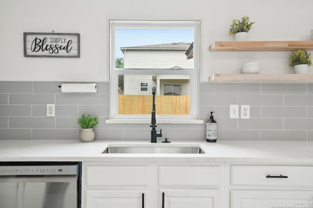 242 Butternut, San Antonio, TX 78245 - kitchen with stainless steel dishwasher, a sink, tasteful backsplash, white cabinetry, and light countertops