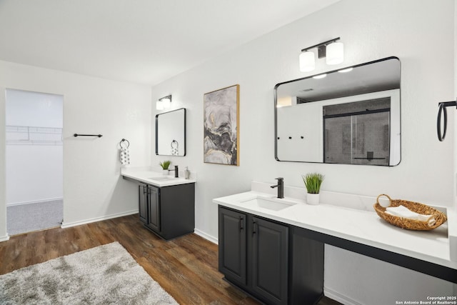 242 Butternut, San Antonio, TX 78245 - full bathroom featuring wood finished floors, two vanities, a shower with shower door, a walk in closet, and baseboards