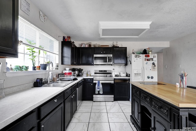 1515 Agency, San Antonio, TX 78245 - kitchen featuring stainless steel appliances, a sink, dark cabinets, light marble finish floors, and wood counters