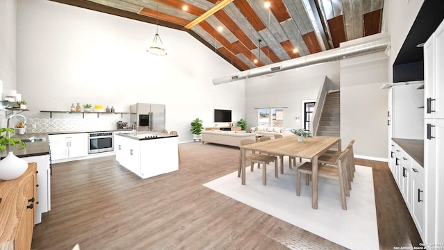 201 Lakeview Cir, La Vernia, TX 78121 - kitchen with stainless steel appliances, a sink, high vaulted ceiling, white cabinets, and hanging light fixtures