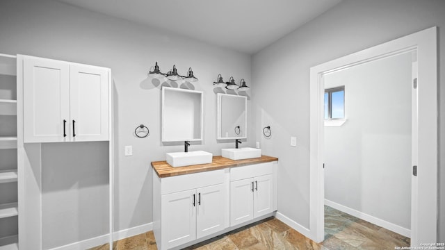 201 Lakeview Cir, La Vernia, TX 78121 - bathroom with double vanity, stone finish floors, and baseboards