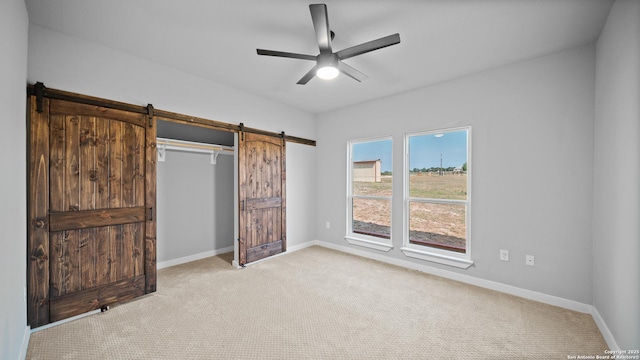 201 Lakeview Cir, La Vernia, TX 78121 - unfurnished bedroom featuring a barn door, carpet, and baseboards