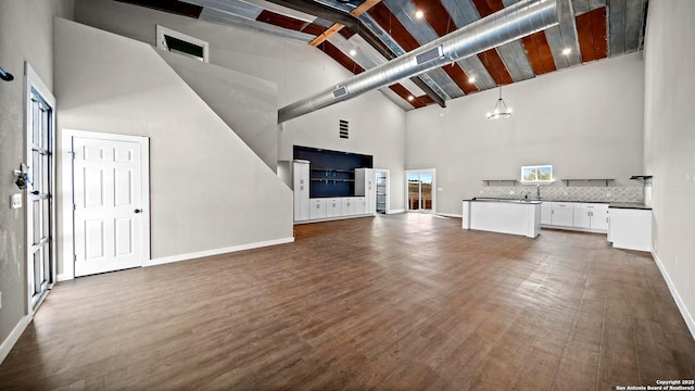201 Lakeview Cir, La Vernia, TX 78121 - unfurnished living room with high vaulted ceiling, beamed ceiling, dark wood-style floors, baseboards, and a chandelier