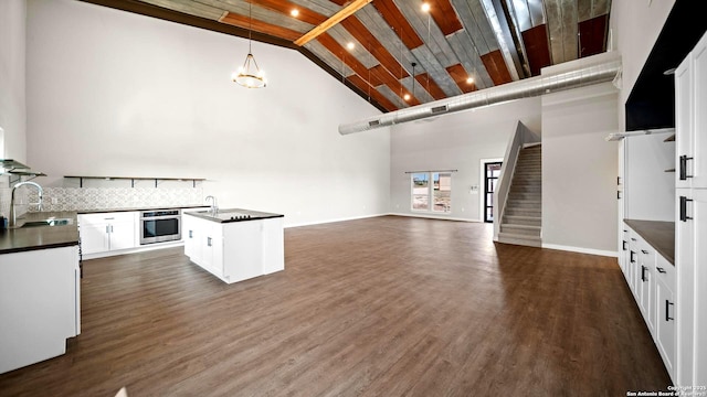 201 Lakeview Cir, La Vernia, TX 78121 - kitchen featuring stainless steel oven, dark countertops, a sink, open floor plan, and high vaulted ceiling