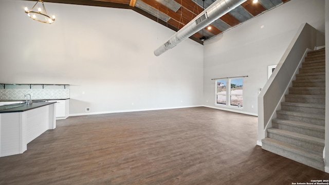 201 Lakeview Cir, La Vernia, TX 78121 - unfurnished living room featuring high vaulted ceiling, stairs, dark wood-style flooring, a chandelier, and baseboards