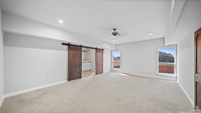 201 Lakeview Cir, La Vernia, TX 78121 - unfurnished bedroom featuring a barn door, light colored carpet, multiple windows, and recessed lighting