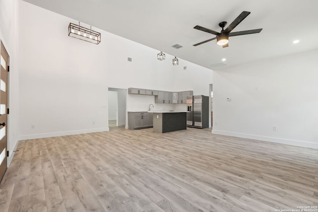 259 Future, San Antonio, TX 78213 - unfurnished living room with high vaulted ceiling, baseboards, light wood-style flooring, a ceiling fan, and a sink