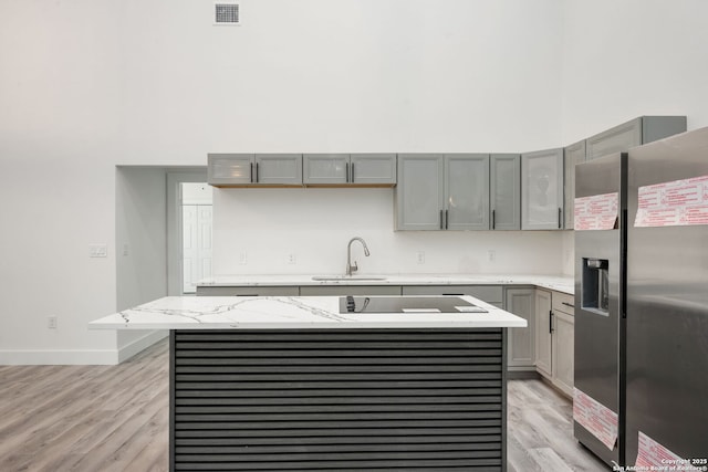 259 Future, San Antonio, TX 78213 - kitchen featuring stainless steel fridge, a sink, gray cabinetry, light wood-style floors, and a high ceiling