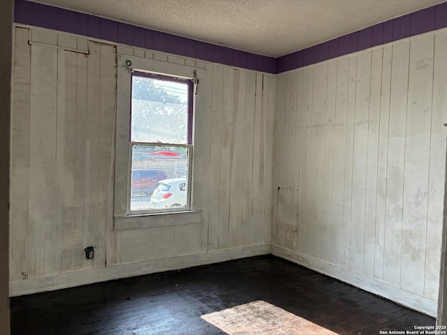 402 Pruitt, San Antonio, TX 78204 - spare room with hardwood / wood-style flooring, a textured ceiling, wooden walls, and baseboards
