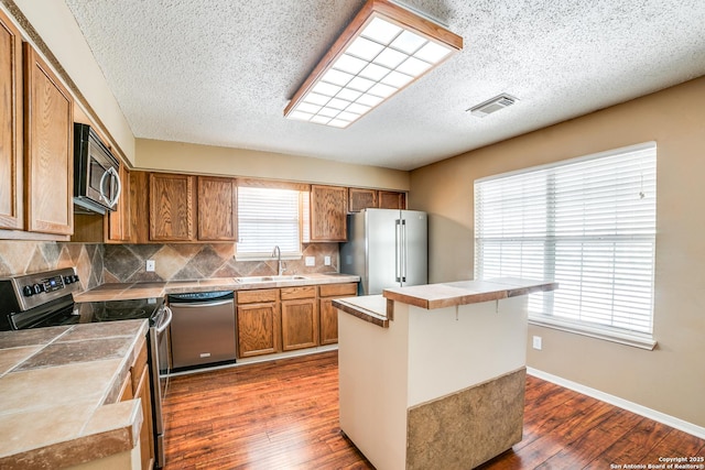 756 County Road 245, Hondo, TX 78861 - kitchen featuring appliances with stainless steel finishes, a sink, tile countertops, brown cabinets, and a textured ceiling
