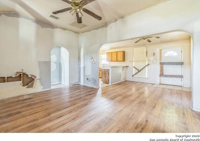 2514 Christian, San Antonio, TX 78222 - unfurnished living room with arched walkways, a ceiling fan, and light wood-type flooring