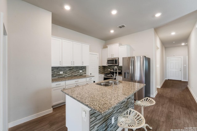 6955 Shiraz Way, Converse, TX 78109 - kitchen with stainless steel appliances, a sink, dark wood-style flooring, backsplash, and a breakfast bar area