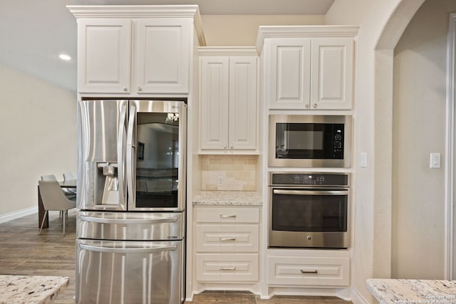 7938 Cibolo, Boerne, TX 78015 - kitchen featuring appliances with stainless steel finishes, wood finished floors, light stone countertops, baseboards, and backsplash