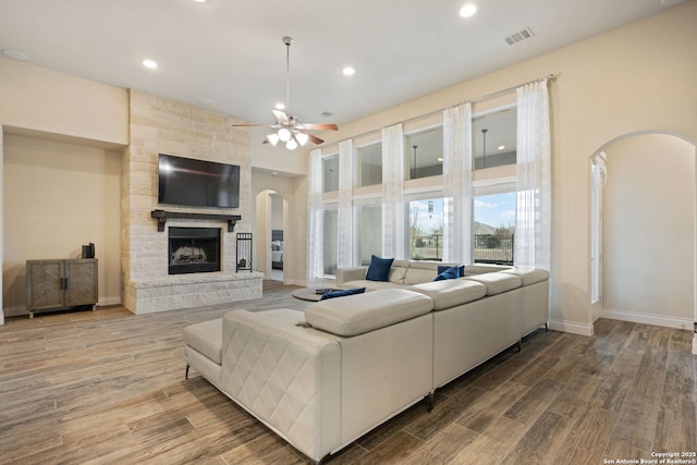 7938 Cibolo, Boerne, TX 78015 - living room featuring arched walkways, wood finished floors, ceiling fan, a stone fireplace, and recessed lighting