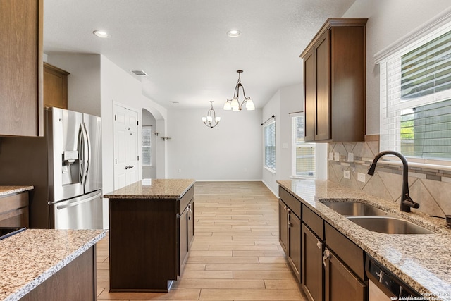 11423 Roadrunner, San Antonio, TX 78245 - kitchen with a sink, a chandelier, backsplash, arched walkways, and stainless steel appliances