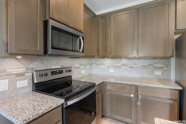 11423 Roadrunner, San Antonio, TX 78245 - kitchen featuring stainless steel appliances, backsplash, and light stone counters