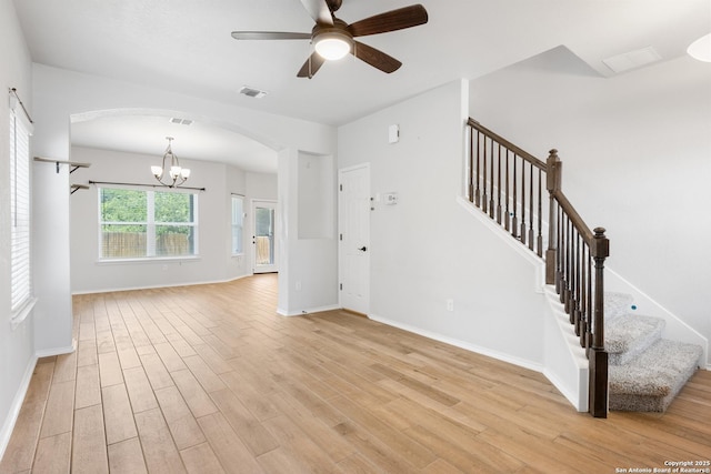 11423 Roadrunner, San Antonio, TX 78245 - unfurnished living room featuring arched walkways, light wood-style floors, ceiling fan, stairway, and baseboards