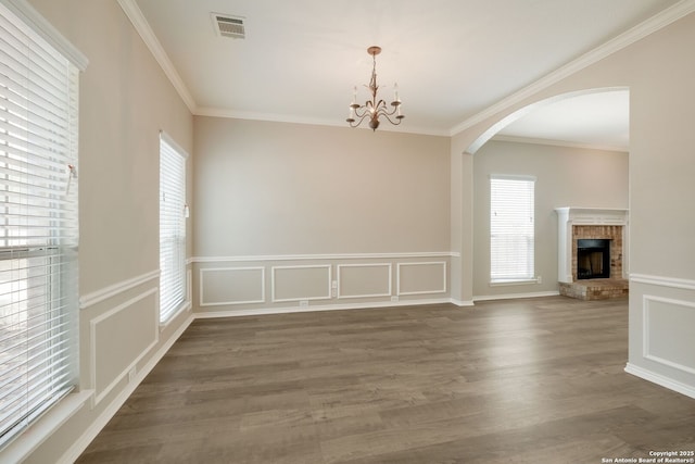 543 Willow Grove Dr, San Antonio, TX 78245 - unfurnished dining area featuring healthy amount of natural light, arched walkways, a brick fireplace, a chandelier, and crown molding