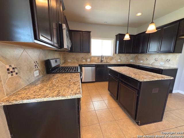12012 Ivy Post, Schertz, TX 78154 - kitchen with stainless steel appliances, a sink, light stone counters, light tile patterned floors, and a kitchen island