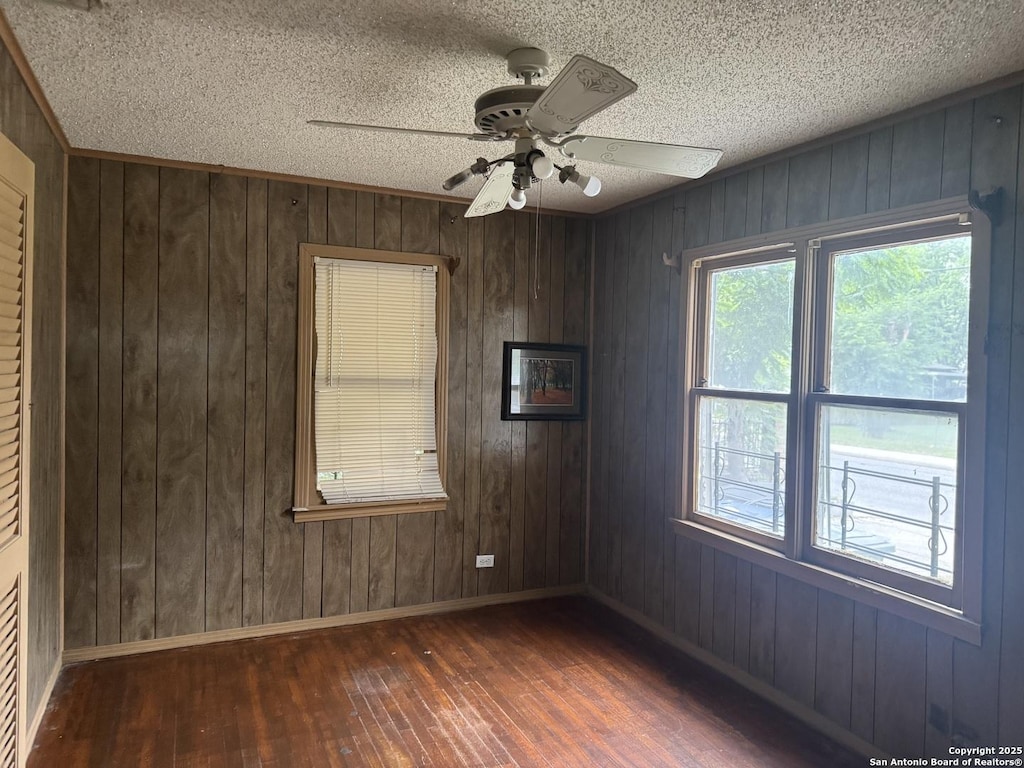 907 Recio, San Antonio, TX 78225 - empty room with hardwood / wood-style flooring, baseboards, a ceiling fan, wood walls, and a textured ceiling