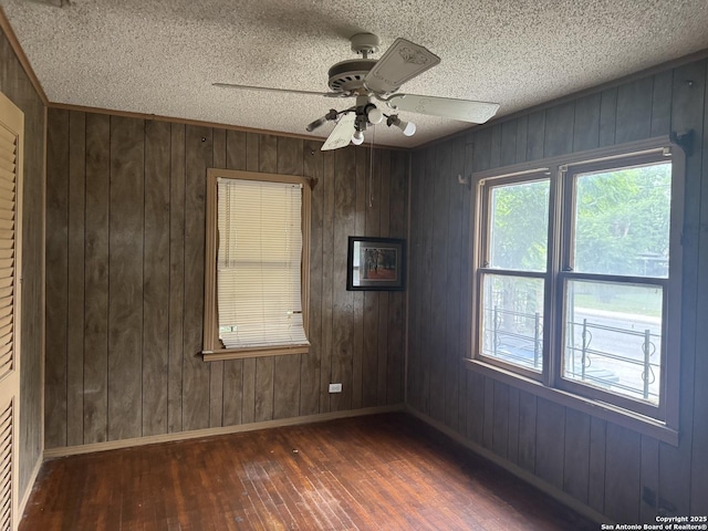 907 Recio, San Antonio, TX 78225 - empty room with hardwood / wood-style flooring, baseboards, a ceiling fan, wood walls, and a textured ceiling