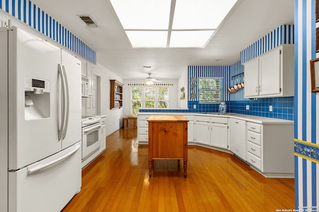 557 Timber Holw, New Braunfels, TX 78132 - kitchen featuring white appliances, light wood-style floors, a ceiling fan, white cabinets, and a center island