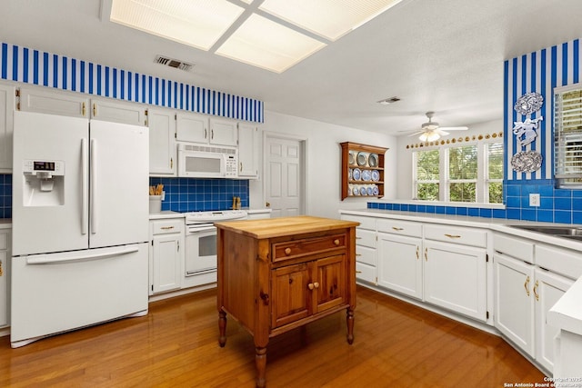 557 Timber Holw, New Braunfels, TX 78132 - kitchen with white appliances, dark wood finished floors, decorative backsplash, and white cabinets