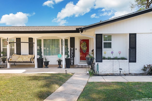 311 Redcliff, San Antonio, TX 78216 - doorway to property featuring covered porch, a lawn, and brick siding