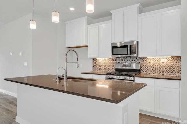 771 Fort Leonard, San Antonio, TX 78245 - kitchen featuring appliances with stainless steel finishes, a sink, dark countertops, light wood-style floors, and a kitchen island with sink