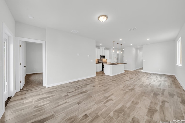 771 Fort Leonard, San Antonio, TX 78245 - unfurnished living room with a sink, light wood-style flooring, baseboards, and recessed lighting