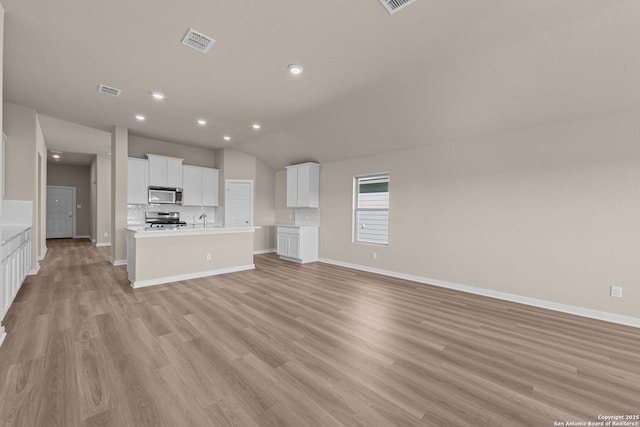22111 Jordans Pl, San Antonio, TX 78264 - unfurnished living room with light wood-style floors, vaulted ceiling, recessed lighting, baseboards, and a sink