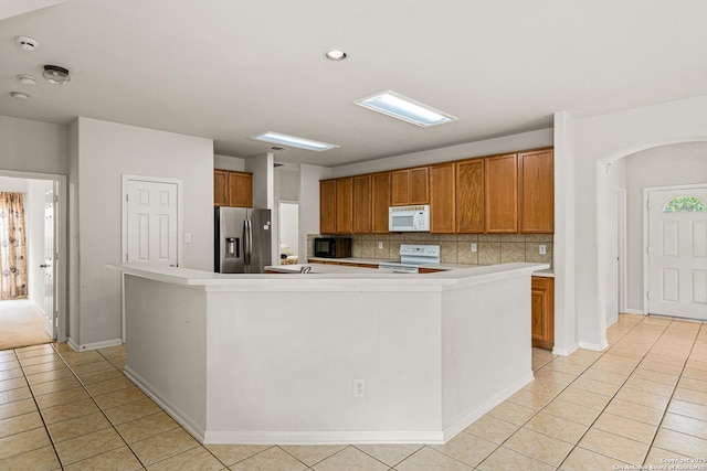 22207 Impala Peak, San Antonio, TX 78259 - kitchen featuring white appliances, light tile patterned floors, decorative backsplash, brown cabinetry, and a large island