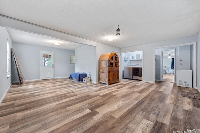 1215 Amanda, Canyon Lake, TX 78133 - unfurnished living room featuring wood finished floors, independent washer and dryer, baseboards, and a textured ceiling