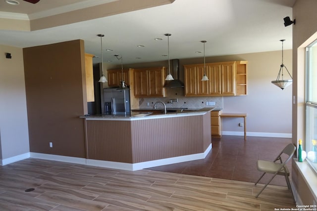178 Spring Creek Cir, Bandera, TX 78003 - kitchen with wall chimney range hood, stainless steel fridge with ice dispenser, backsplash, a peninsula, and hanging light fixtures