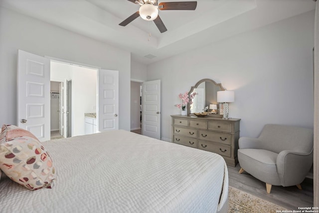 11212 Schmidt Ln, Converse, TX 78109 - bedroom with a walk in closet, light wood-type flooring, ceiling fan, a closet, and a raised ceiling