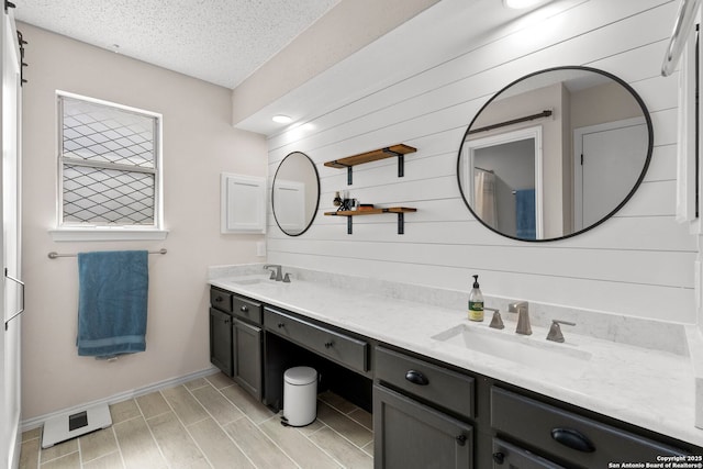 7306 Park W, San Antonio, TX 78250 - full bathroom featuring double vanity, a textured ceiling, baseboards, wood finished floors, and wood walls