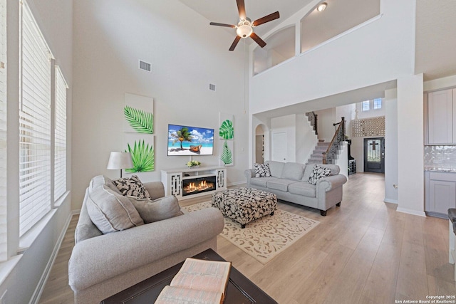 112 La Cima, Boerne, TX 78006 - living room with a warm lit fireplace, a towering ceiling, ceiling fan, healthy amount of natural light, and stairs