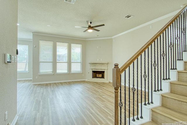 12902 Gypsophila, San Antonio, TX 78253 - unfurnished living room with wood finished floors, a ceiling fan, a fireplace with raised hearth, crown molding, and stairway