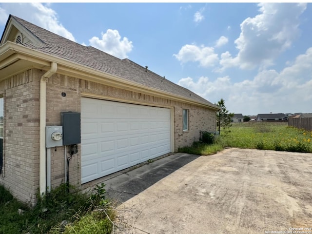 135 Muirfield Ln, Vernia, TX 78121 - view of side of property featuring brick siding, concrete driveway, roof with shingles, and a garage