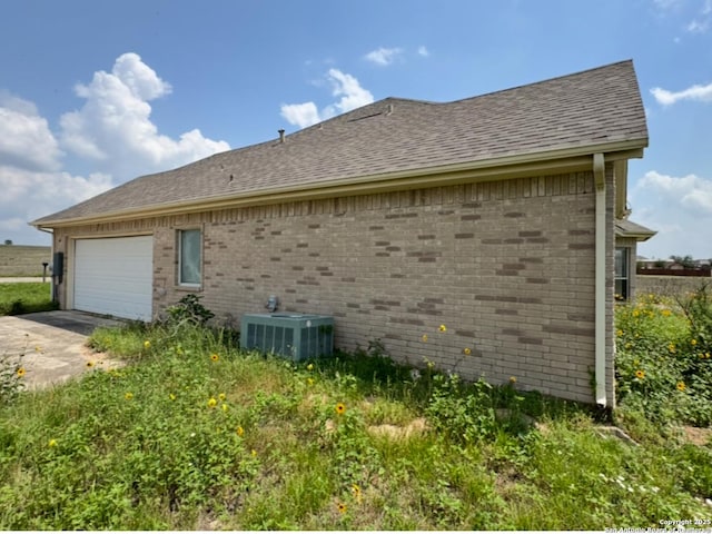 135 Muirfield Ln, Vernia, TX 78121 - view of side of home featuring central air condition unit, brick siding, concrete driveway, and an attached garage