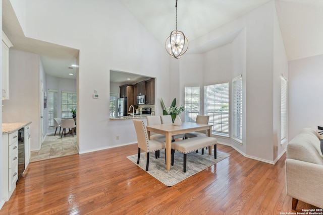 17915 Crystal Knl, San Antonio, TX 78258 - dining space with light wood finished floors, a chandelier, high vaulted ceiling, and baseboards