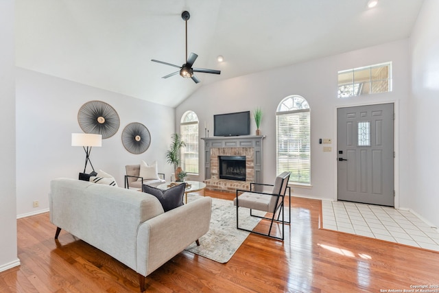 17915 Crystal Knl, San Antonio, TX 78258 - living area with light wood-type flooring, ceiling fan, vaulted ceiling, a fireplace, and baseboards