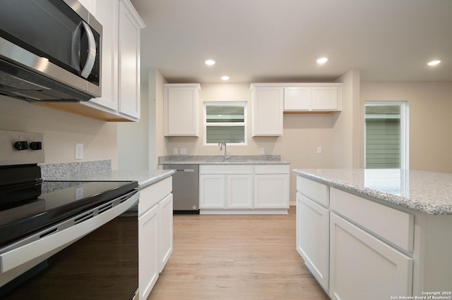 8570 Redhawk Lp, San Antonio, TX 78222 - kitchen with appliances with stainless steel finishes, light wood finished floors, white cabinets, recessed lighting, and a sink