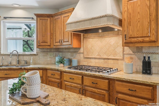 15643 Cloud Top, San Antonio, TX 78248 - kitchen featuring premium range hood, a sink, stainless steel gas stovetop, decorative backsplash, and brown cabinetry