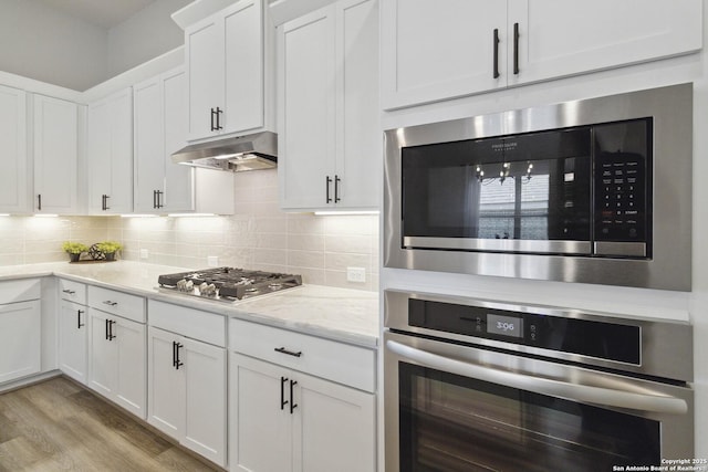 146 Beaver Bnd, Boerne, TX 78006 - kitchen with stainless steel appliances, white cabinetry, under cabinet range hood, and backsplash