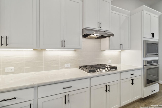 146 Beaver Bnd, Boerne, TX 78006 - kitchen featuring appliances with stainless steel finishes, under cabinet range hood, white cabinets, dark wood-type flooring, and tasteful backsplash