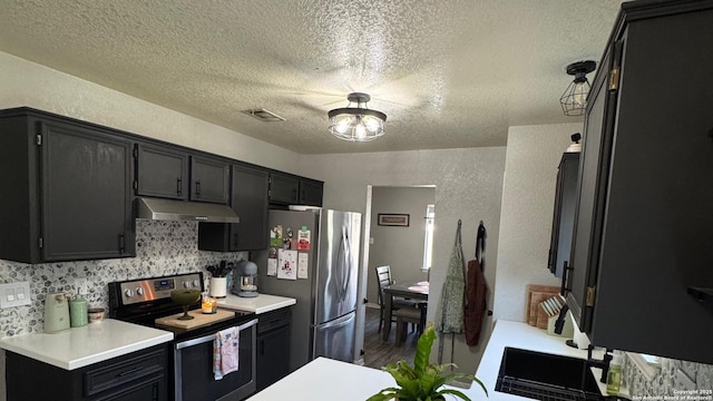 1817 Dusk Dr, Killeen, TX 76543 - kitchen featuring stainless steel appliances, under cabinet range hood, a textured ceiling, dark cabinetry, and light countertops