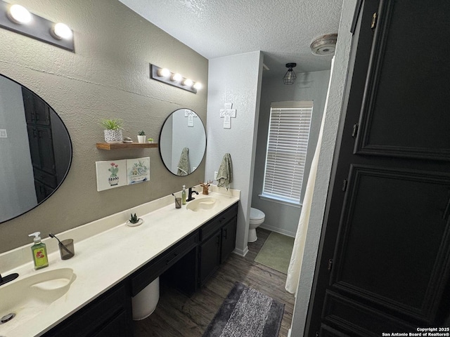 1817 Dusk Dr, Killeen, TX 76543 - bathroom featuring wood finished floors, double vanity, a textured ceiling, a textured wall, and toilet