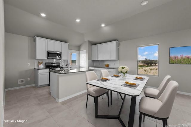 8622 Smithers Ave, San Antonio, TX 78252 - kitchen featuring stainless steel appliances, a center island with sink, tasteful backsplash, lofted ceiling, and dark countertops