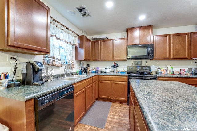 8514 Bayliss Pt, San Antonio, TX 78252 - kitchen with black appliances, a sink, light wood finished floors, recessed lighting, and brown cabinetry
